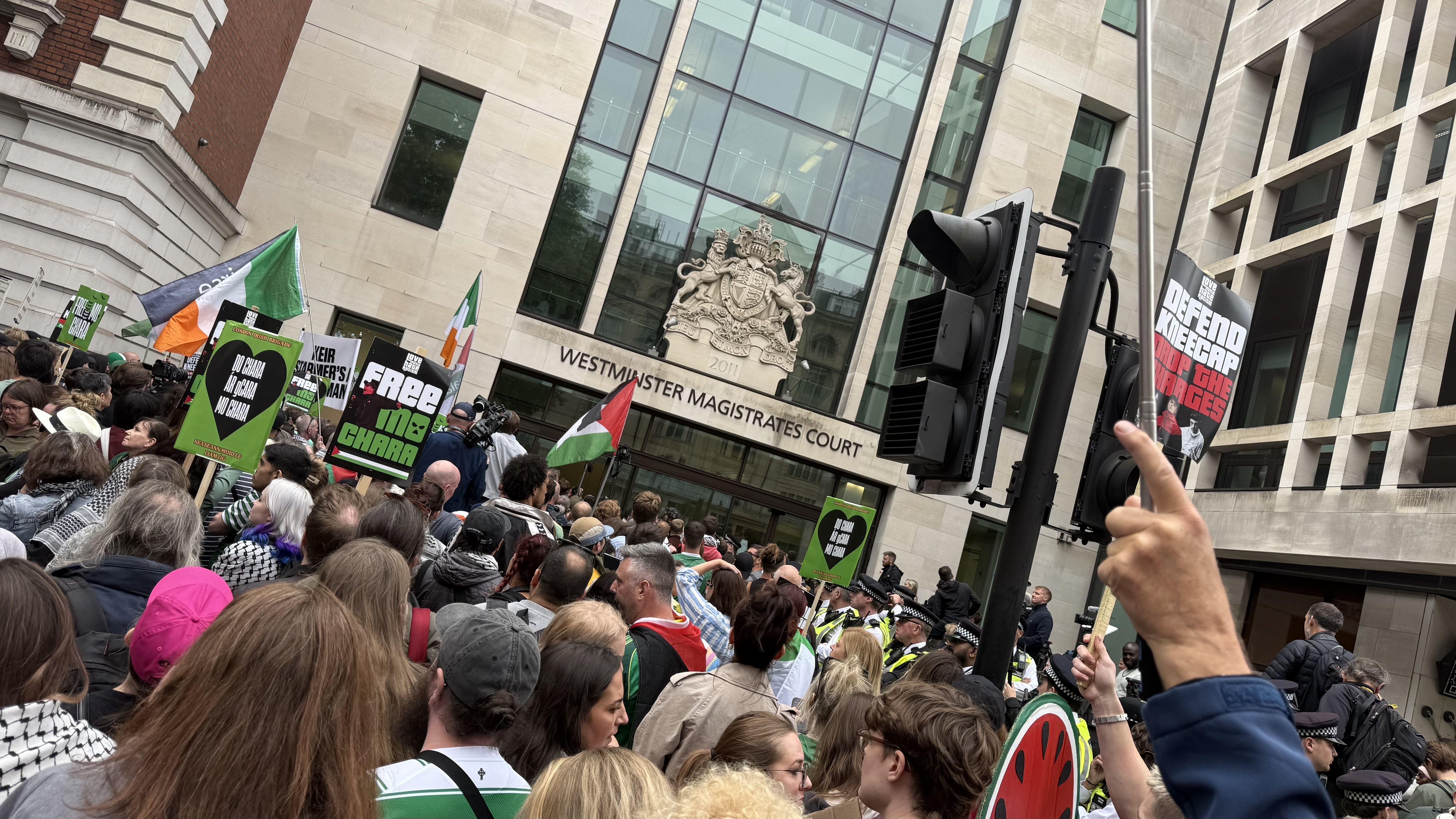 Westminster Magistrates Court With people holding banners, placards and flags, police and TV crews.