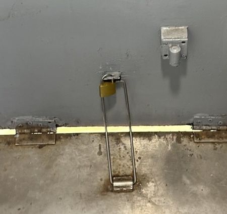 A small brass padlock keeping a keeping a train door closed