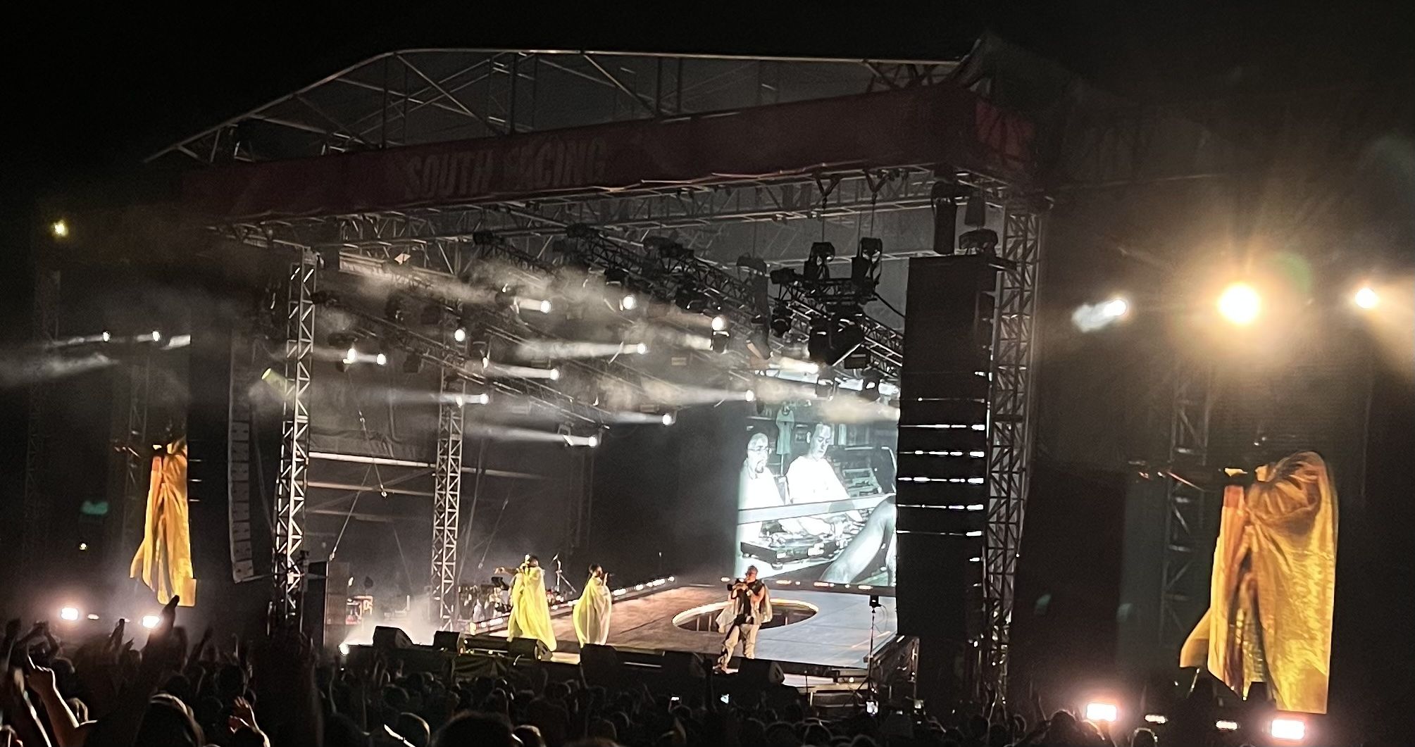 Basement Jaxx live on stage there a two singers at the front wearing yellow costumes